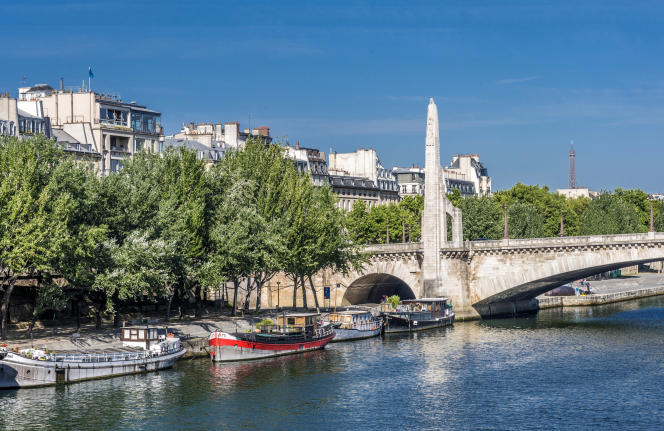 The statue of Saint Geneviève sits atop a stone pinnacle of the Pont de la Tournelle, in Paris.