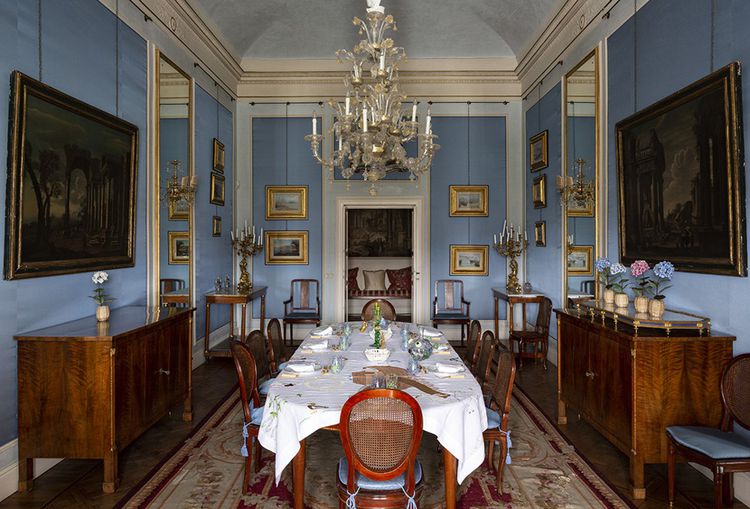 The dining room has palatial proportions.  Its elegant rigor is softened by porcelain flowers by Samuel Mazy and by a tablecloth embroidered in Florence.