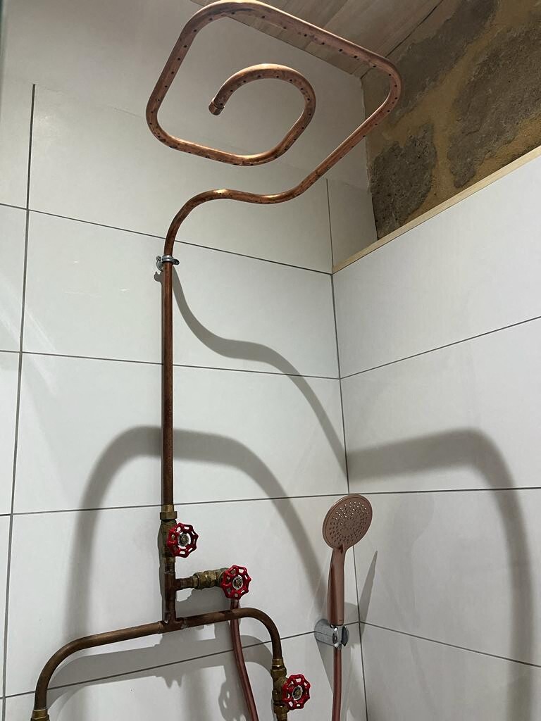 The shower column was created by the plumber with copper pipes.