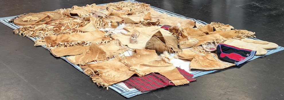 Caribou clothing, snowshoes and tools are displayed on a canvas. 