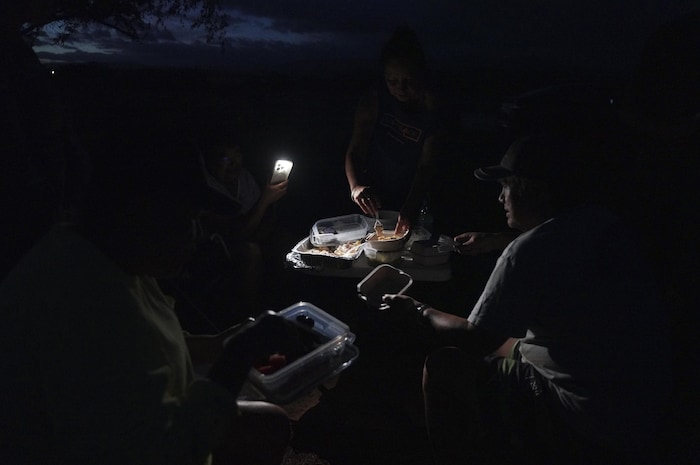 Un groupe de personnes partage un repas dans l'obscurité.