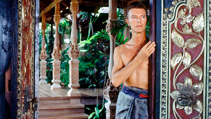 David Bowie posando al lado de una puerta balinesa de su villa ubicada en la exclusiva Isla de Mustique